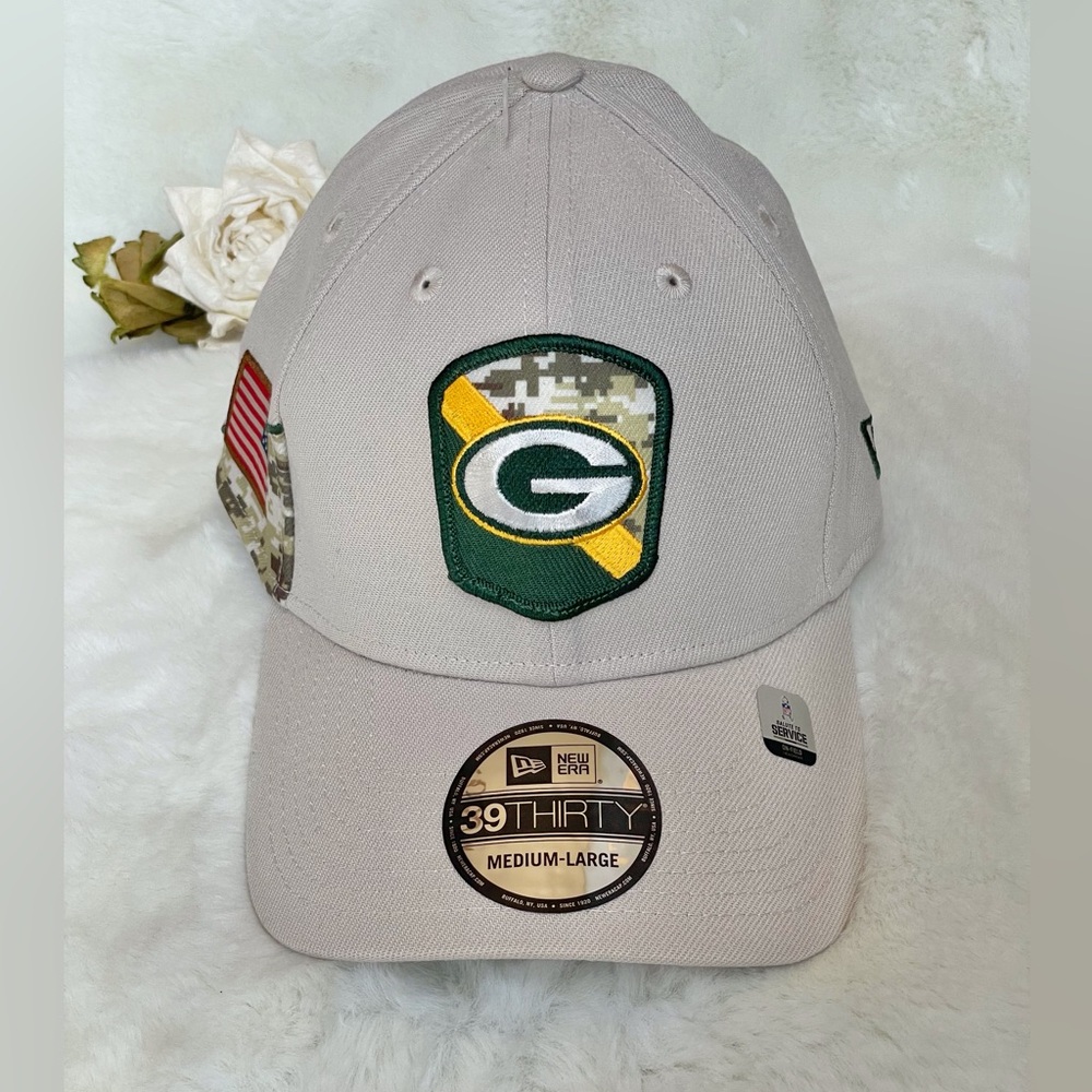 New with tag GREEN BAY PACKERS OFFICIAL NFL HAT. CREAM w/CAMO & flag side SZ M/L